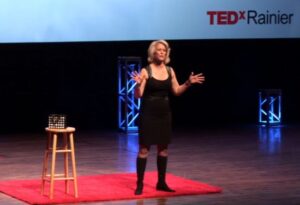 Lesliie Morgam Steiner on a stage presenting a Ted Talk about hr story of domestic violence