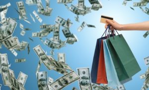 overspending illustrated with dollars flying around shopping bags