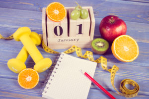 calendar set to Jan.1, fruits, a tape measure and weights for new year's resolutions