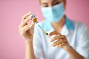 nurse filling syringe with Covid-19 vaccine