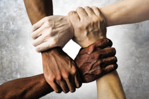 four clasped hands of varying skin colors to illustrate post on combatting discrimination