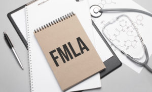 stethescope, pen and notebook saying FMLA on a table