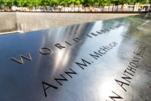 9-11 NYC Memorial - stone with names in foreground with fountains and memorial in the background