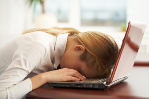 young businesswoman asleep with her head on her laptop, a victim of Zoom fatigue