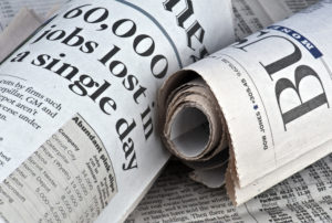 newspapers with headlines about layoffs and job loss