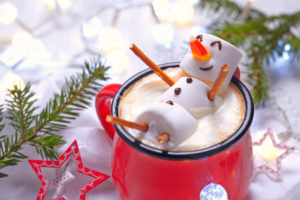 Red mug with hot chocolate with melted marshmallow snowman to illustrate 2022 Holiday Survival Toolkit