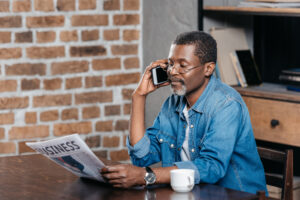 middle-aged black man in a cafe reading HR News Roundup and talking on cell phone