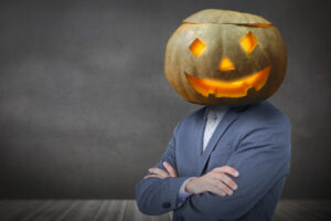Person in a suit standing with folded arms and wearing a jac on lantern head to illustrate the Halloween edition of HR News Roundup.