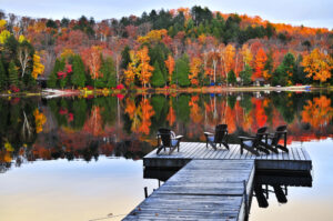 brilliant, colorful autumn foliage scene overlooking a dock on a lake to illustrate key October dates post