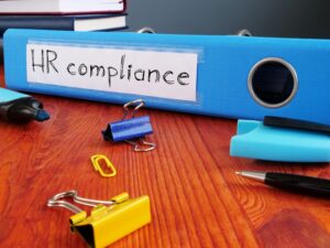 blue notebook on a desk reading HR compliance