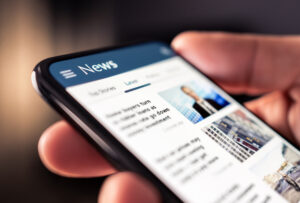 Hand holding a mobile phone with news on the screen. to illustrate the post for HR News.