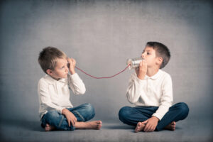 two young boys talking on a tin can telephone to illustrate a post on HR News.